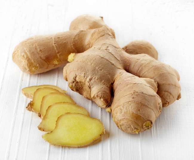 Fresh sliced ginger root on white wooden background